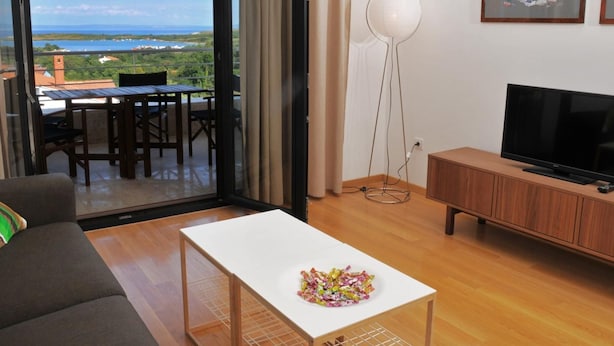 Ein modernes Wohnzimmer mit Balkon, Flachbildfernseher und Essbereich.