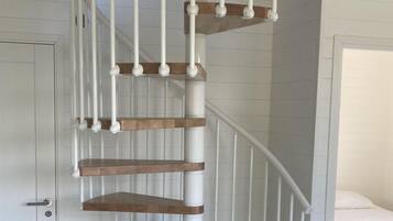 A spiral staircase with white railings and wooden steps, leading to an upper floor.