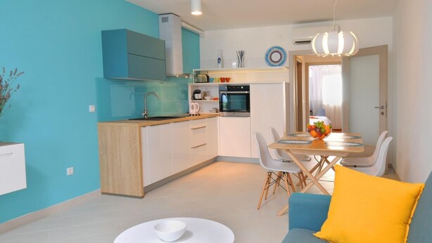 A modern kitchen with a dining area, a sofa, and a small table. - Appartement "Kat mali" mit Blick auf das Wasser by Interhome (Medulin/Ližnjan)