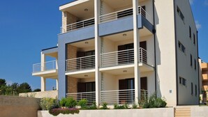 A modern multi-story residential building with balconies, a stone facade, and a landscaped garden area. - Appartement "Kat mali" mit Blick auf das Wasser by Interhome (Medulin/Ližnjan)