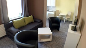 Una sala de estar moderna con un sofá, dos sillones, una mesita de centro y un televisor.