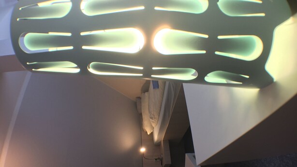 Un interior moderno con una lámpara de techo original, una pared blanca y una pequeña zona de escritorio.