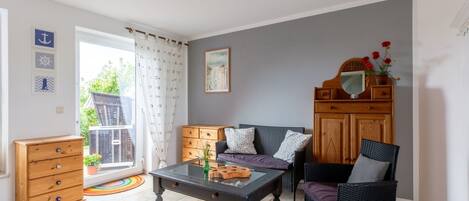 A living room with a sofa, a coffee table, a wooden cabinet, and a chair.