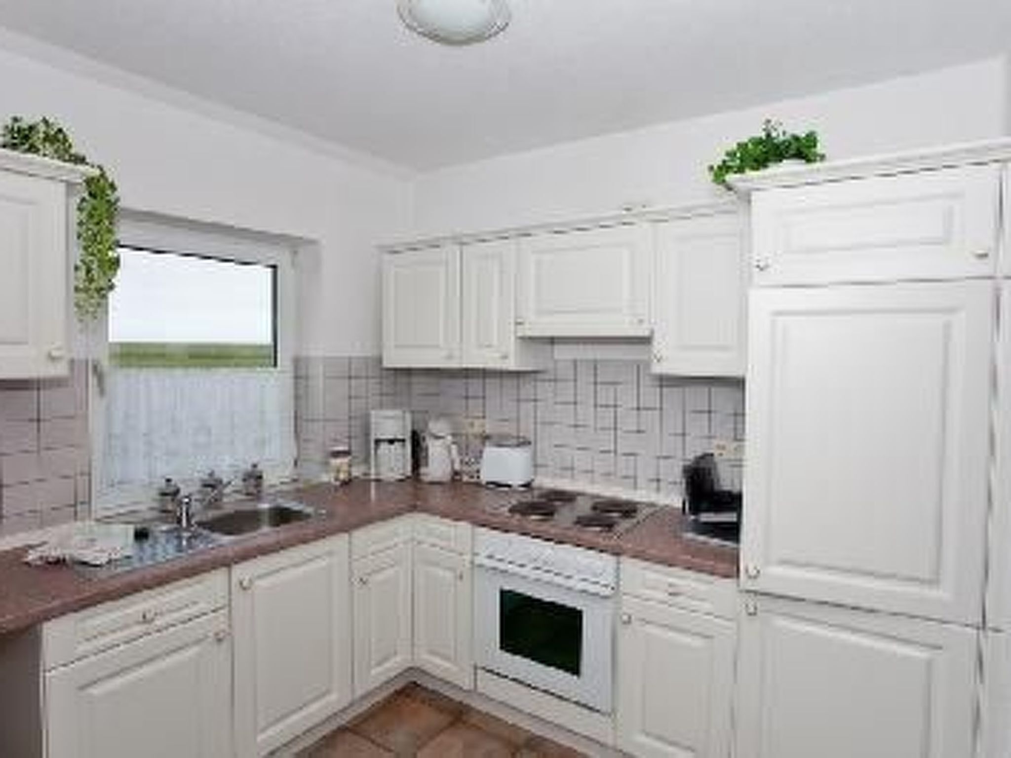 A kitchen with white cabinets, a window, and a microwave.