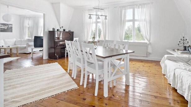A spacious room with a dining table, white chairs, a TV, and a piano. - Rosenhill by Interhome (Pauliström)