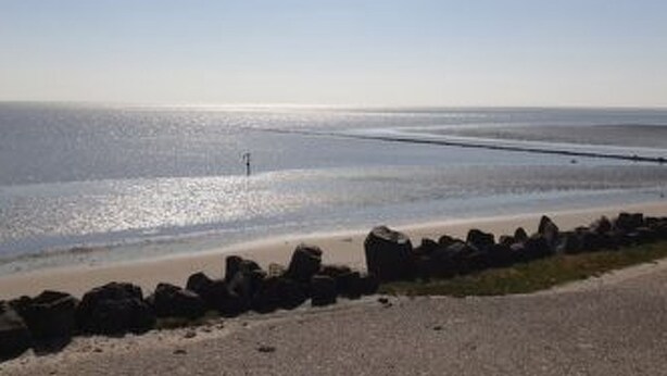 Ein Strand mit felsigem Ufer und blauem Himmel.