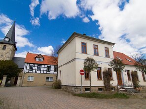 Un bâtiment européen traditionnel, doté d’un clocher, d’une façade blanche et d’un toit recouvert de tuiles rouges.
