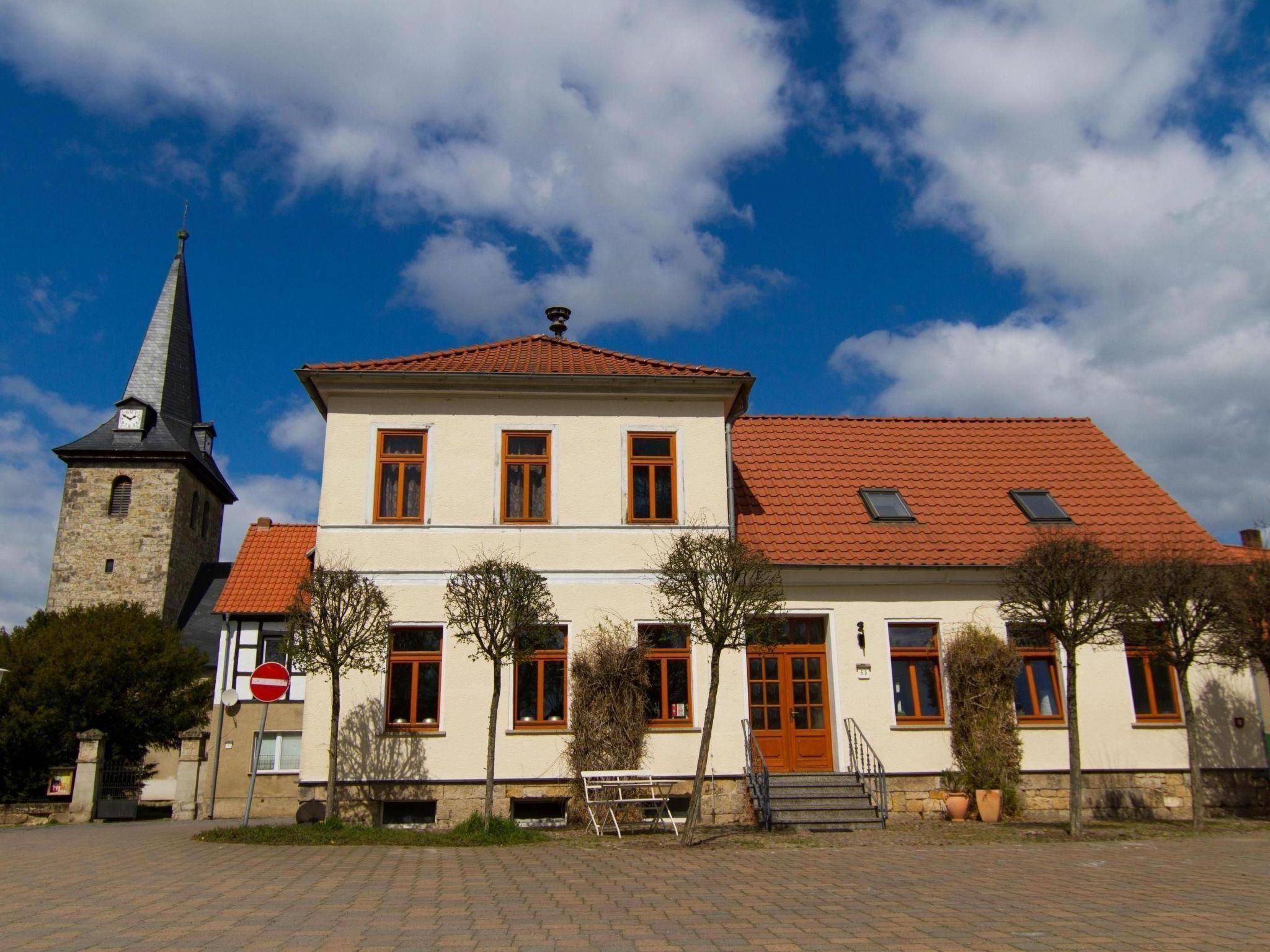 A two-story building with a red-tiled roof and a stone tower.