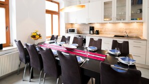 A modern dining area with a long table set for six, surrounded by dark chairs. A kitchen with white cabinets and a wooden countertop is visible in the background. - in Radisleben mit Garten und Terrasse by Interhome (Ballenstedt)