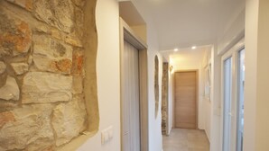 A hallway with stone walls, a wooden door, and a glass door leading to a balcony. - Stilvolle Wohnung in Arena mit großer Terrasse by Interhome (Pula)