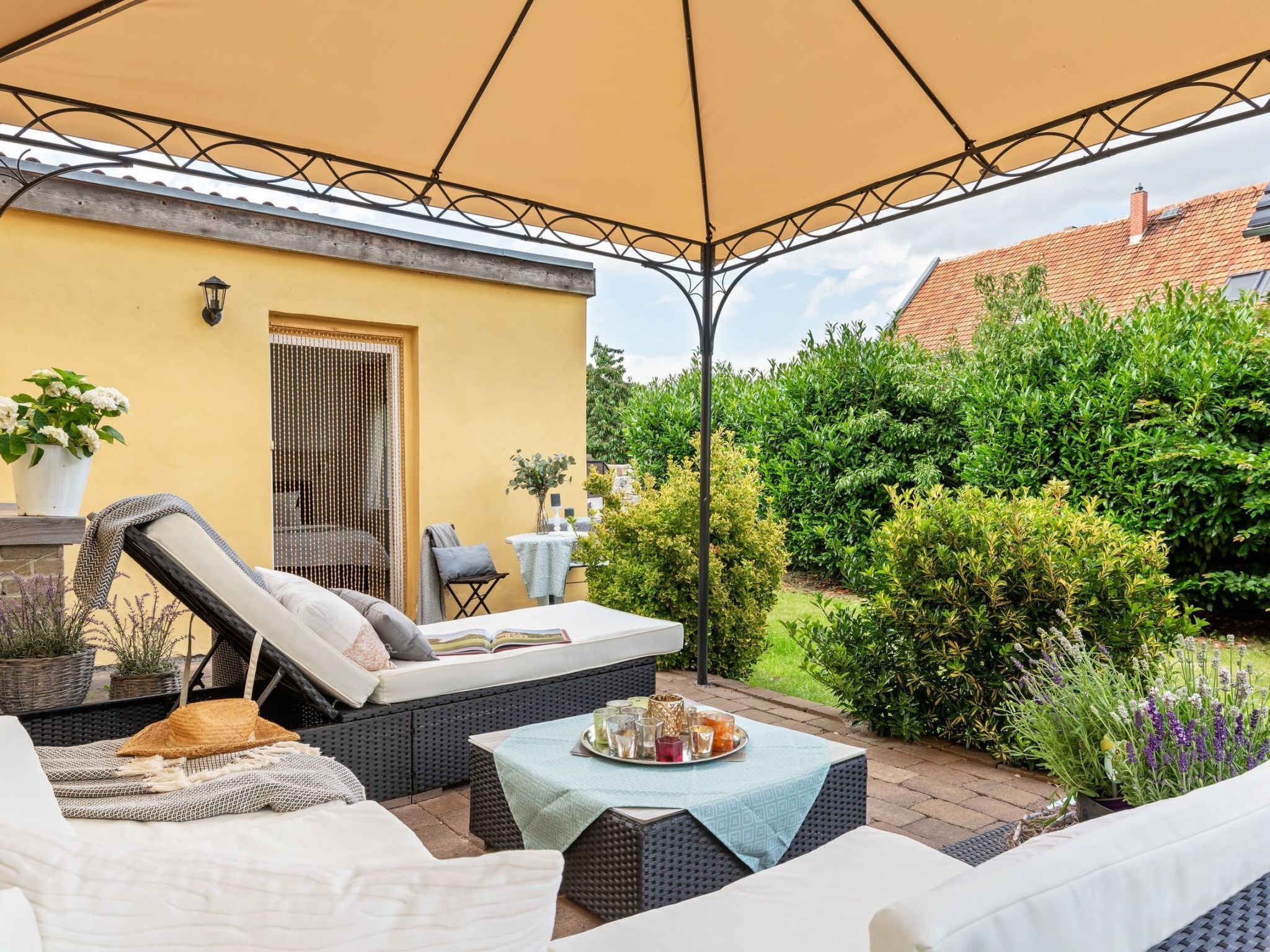 Een terras met buitenmeubilair, een tafel met drankjes en een gele muur.