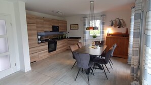 Una cocina moderna con armarios de madera, una mesa de comedor con sillas e iluminación colgante.