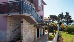 Ein mehrstöckiges Gebäude mit Backsteinfassade, einem Balkon mit Metallgeländer und Blick auf ein Gewässer im Hintergrund.