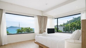 A modern bedroom with a large bed, a TV, and a view of the ocean. - Aqua Maya Phuket (Patong)