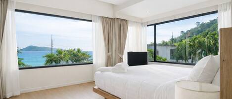 Un dormitorio moderno con una cama grande, un televisor y vistas al océano.