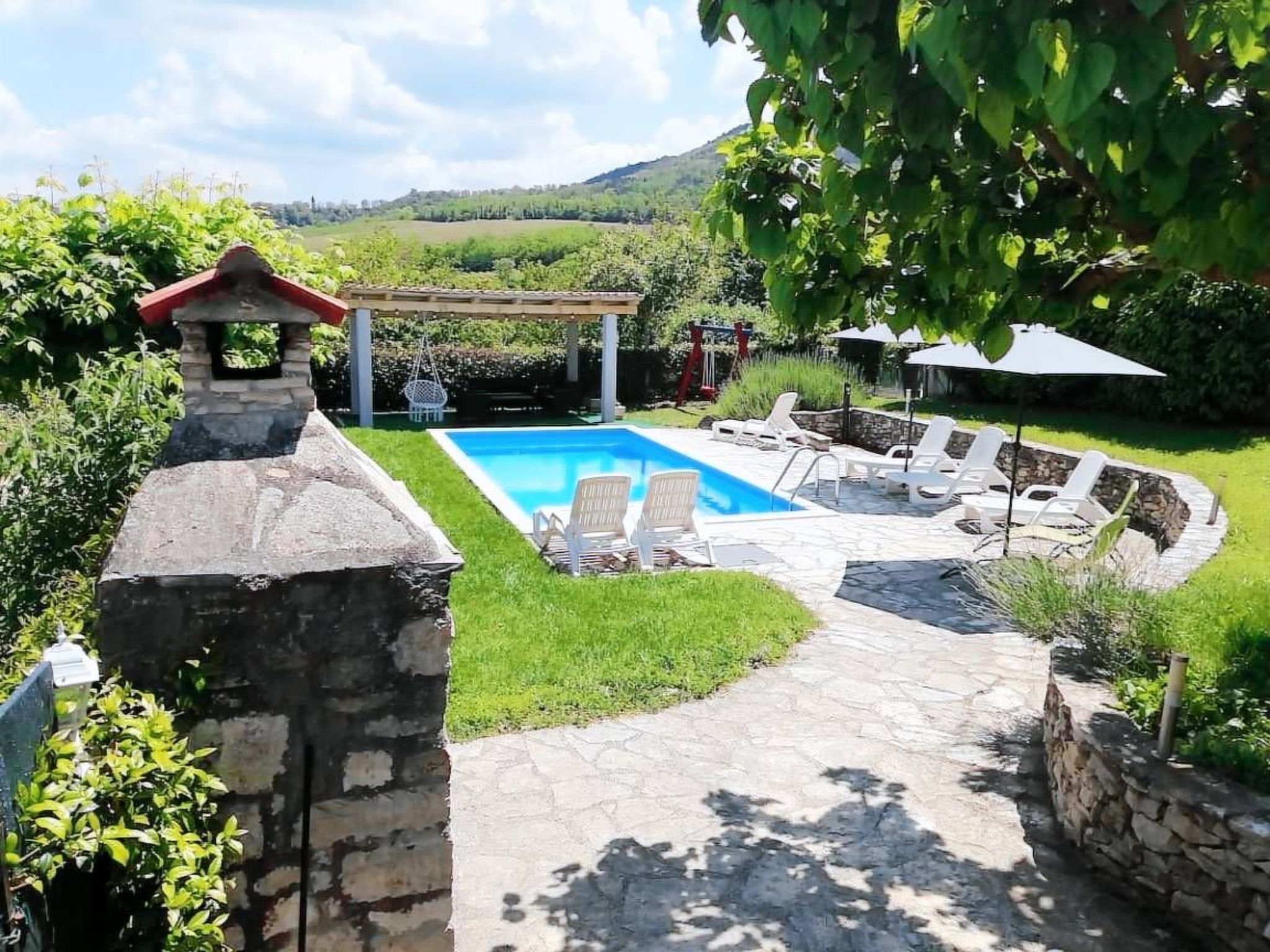 A backyard with a swimming pool, lounge chairs, and a stone pathway.