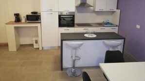 A compact kitchen with white cabinets, a microwave, an oven, a sink, and two bar stools. - "Valentino" mit Blick auf das Wasser by Interhome (Motovun)