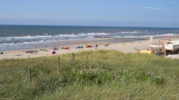 A beach with a lifeguard tower and a grassy area in the foreground. - Gemütliches Ferienhaus De Blenck by Interhome (Callantsoog)