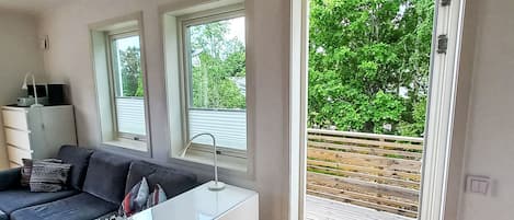A modern living room with a sofa, a glass coffee table, and a sliding glass door leading to an outdoor deck.