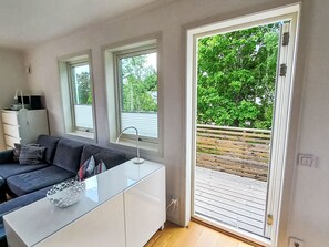 A modern living room with a sofa, a glass coffee table, and a sliding glass door leading to an outdoor deck. - Ljugarn 2 by Interhome (Ljugarn)