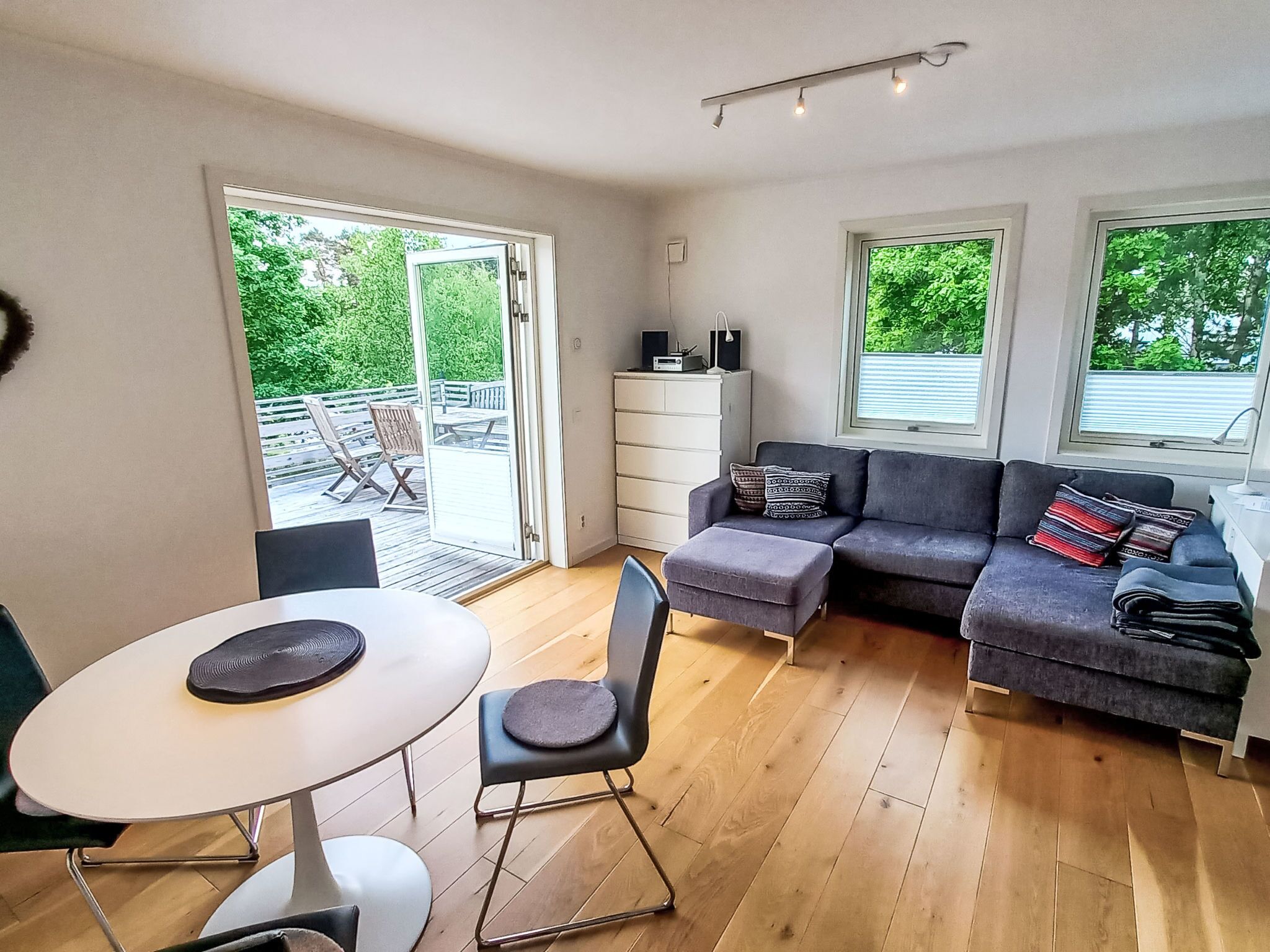 A modern living room with a sofa, a dining table, and a view of the outdoors.