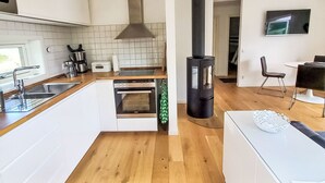 A modern kitchen with a stove, oven, and a black wood stove. - Ljugarn 2 by Interhome (Ljugarn)