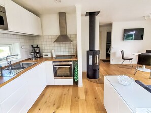 A modern kitchen with a stove, oven, and a black wood stove. - Ljugarn 2 by Interhome (Ljugarn)