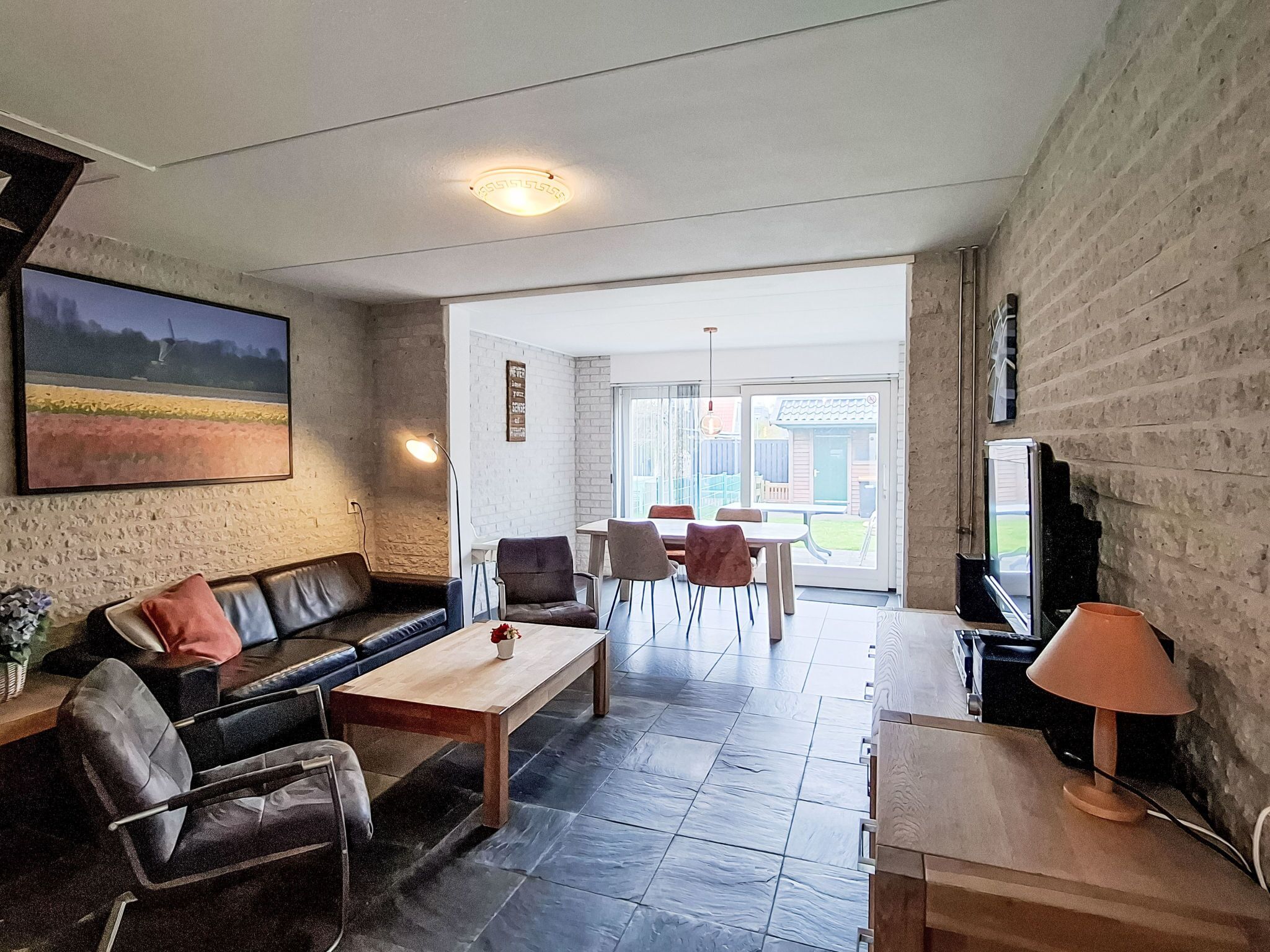 A living room with a sofa, coffee table, and chairs, a television, and a view of the outdoors.