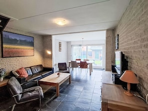 A living room with a sofa, coffee table, and chairs, a television, and a view of the outdoors. - Gemütlicher Bungalow für 4 Personen by Interhome (Callantsoog)