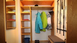 Un espace de rangement compact avec des étagères en bois, un seau bleu et un banc.