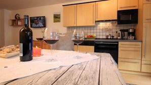 Une cuisine avec des meubles en bois, un four à micro-ondes, une machine à café et une table avec des verres à vin et une bougie.