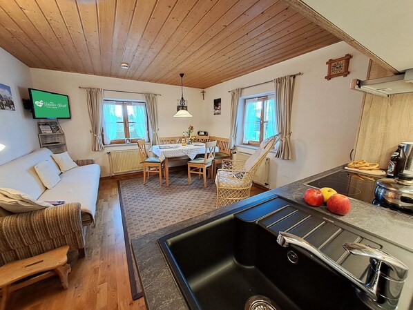 A cozy living room with a sofa, a dining table, and a kitchen area with a sink and stove.