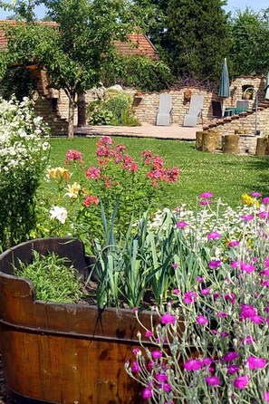 A garden with a variety of flowers and a stone building in the background.