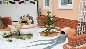 Een tuin met een kleine vijver, decoratieve stenen, een kerstboom en een bakstenen muur.