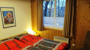 Kodikas huone, jossa on sänky, tuoli, ikkuna, jossa on verhot, ja seinällä oleva kehystetty kuva.