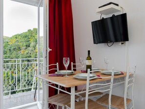 Ein Essbereich mit einem Tisch für vier Personen, einer Weinflasche und einem an der Wand befestigten Fernseher.