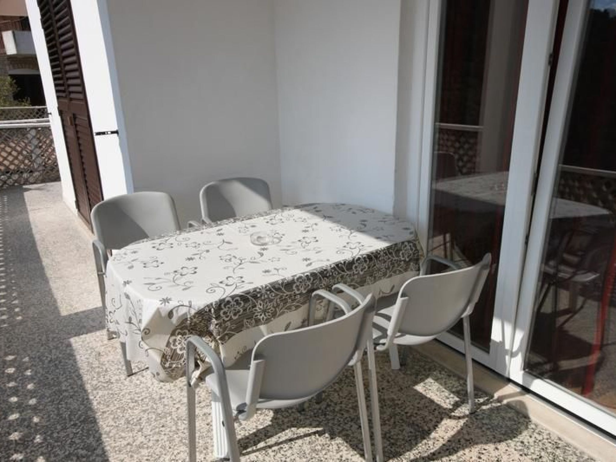 Eine Terrasse im Freien mit Tisch und Stühlen, bedeckt mit einer gemusterten Tischdecke.