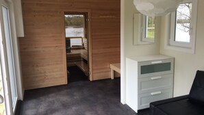 Una habitación moderna con piso de madera, tocador blanco, un banco y un ventanal grande.