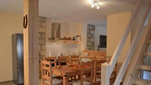 Ein Essbereich mit Holzbänken und einem Tisch, eine Küche mit Steinwänden und eine Treppe.