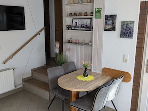 A dining area with a round table, two grey chairs, a vase with flowers, and a staircase leading to another room. - mit Garten, Grill und Terrasse by Interhome (Jessern)