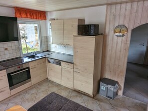 A kitchen with wooden cabinets, a built-in oven, a microwave, and a sink. - mit Garten, Grill und Terrasse by Interhome (Jessern)