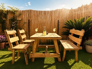 A wooden outdoor table with four chairs, surrounded by a bamboo fence and potted plants. - Dream appartment Jardins Carthage (Tunis)