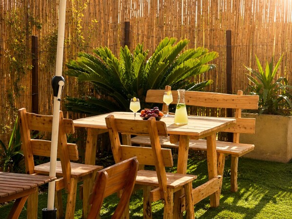 A wooden table with chairs, a bamboo fence, and a grassy area. - Dream appartment Jardins Carthage (Tunis)