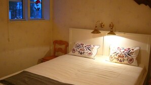 A bedroom with a bed, two bedside lamps, a window with a view of trees, and a chair. - Haus mit toller Aussicht an einem schönen See by Interhome (Hjältevad)