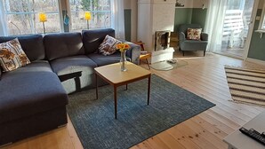 A living room with a sectional sofa, a fireplace, and a view of the outdoors through large windows. - Karlsson by Interhome (Fågelfors)