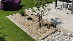 Un patio trasero con piscina, un árbol pequeño, un sillón de mezcla azul y muebles de exterior.