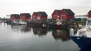 Ein Hafen mit mehreren roten Gebäuden und vertäuten Booten.