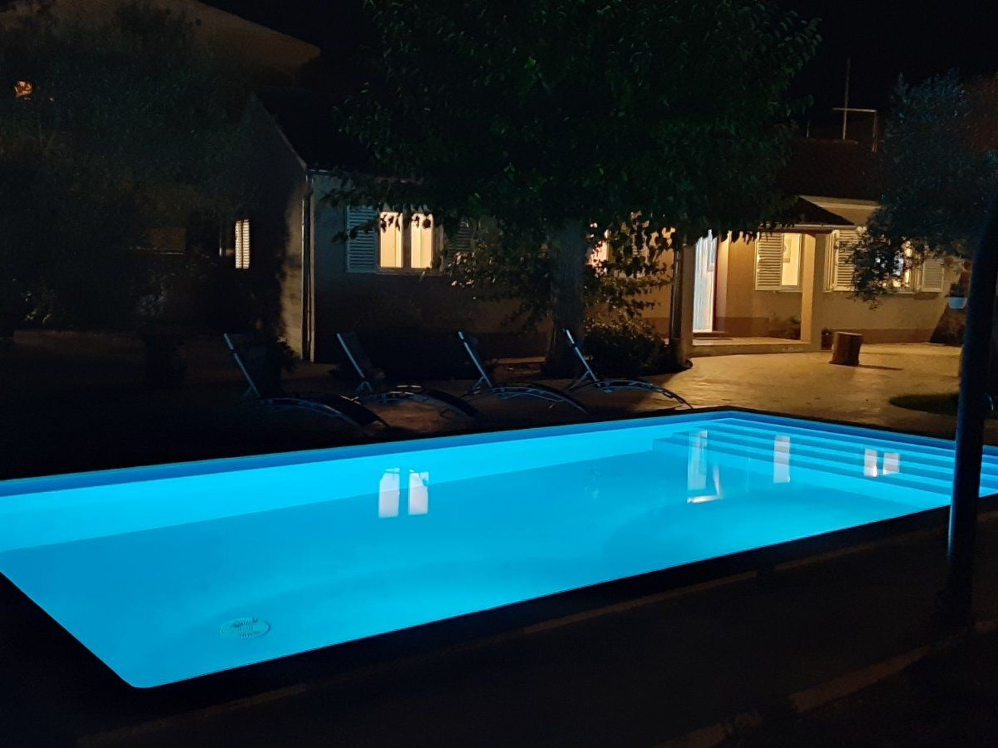 Una piscina con sillones de descanso y un edificio al fondo.