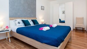 A modern hotel room with a large bed, wooden headboard, and a grey accent wall. - AQUA mit Pool by Interhome (Pula/Banjole)