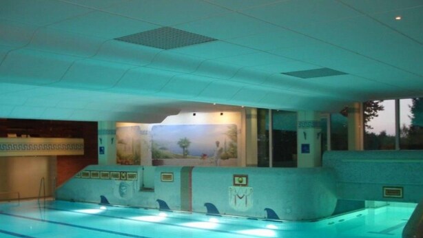 En swimmingpool med baner, et mural på væggen og et flisebeklædt loft.